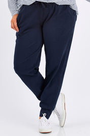 Model Mae wearing size 18 of The Basic Keeper Pant in colour Navy (Blue), from the front, cropped image