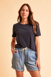 Model Madeline wearing size 10 of The Weekender Chambray Short in colour Blue (Blue), from the front, cropped image
