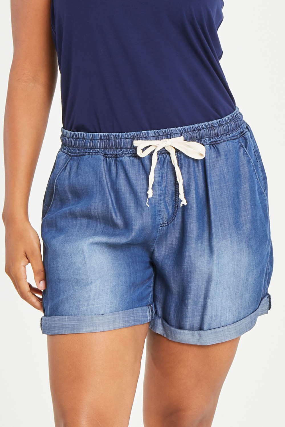 Model Noli wearing size 14 of The Weekender Chambray Short in colour Mediumblue (Blue), from the front, cropped image