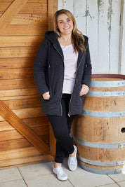 A model wearing size 14 of The Luxe Puffer Jacket in colour Charcoal (Black), from the front, showing the whole outfit