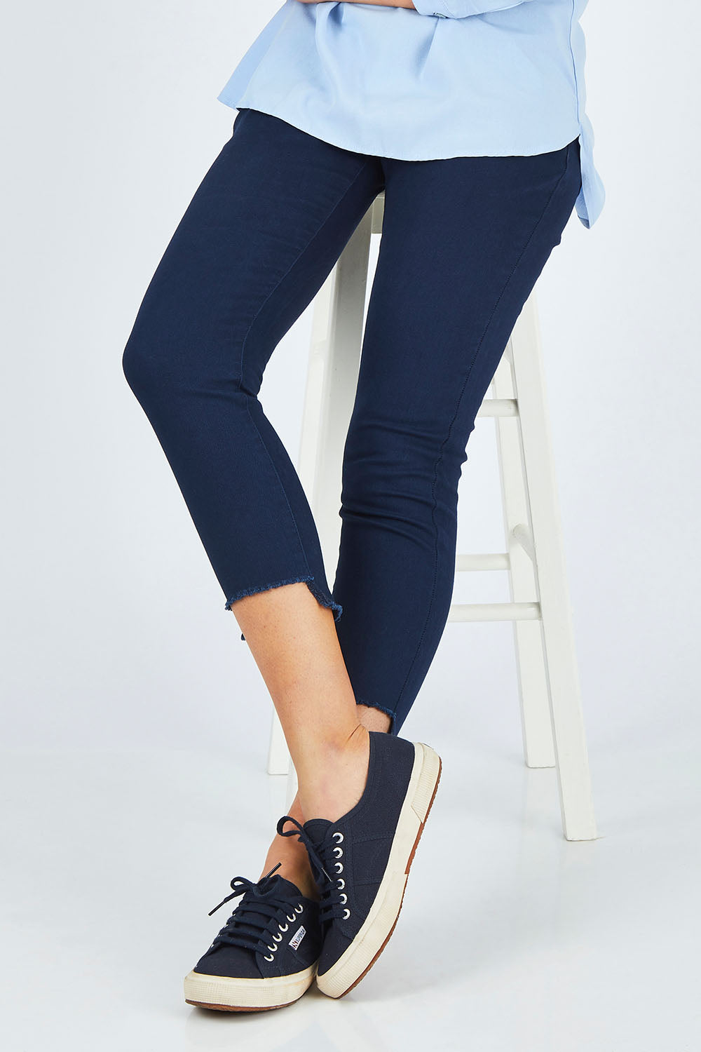 Model Chelsea wearing size 10 of The Skinny Step Hem Jean in colour Blue (Blue), from the front, cropped image