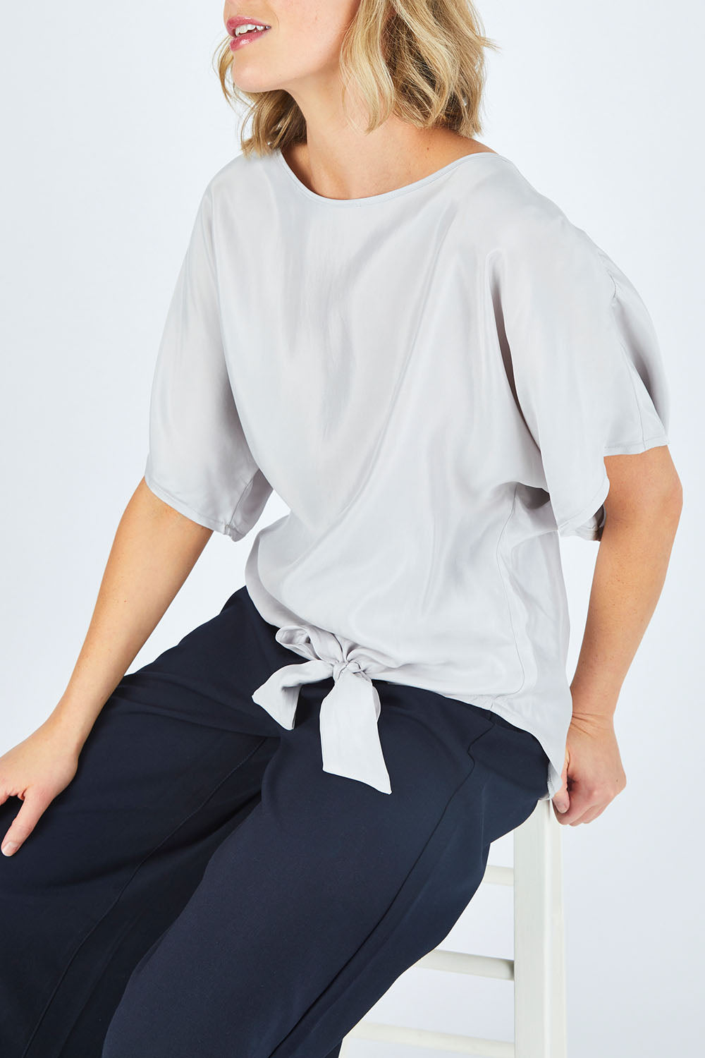 Model Chelsea wearing size 10 of The Luxe Tie Front Top in colour Silver (Grey), from the front, cropped image