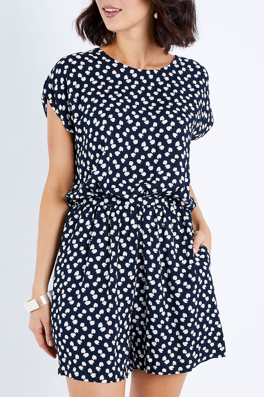 Model Andrea wearing size 10 of The Printed Tie Waist Playsuit in colour Multiprint (Black), from the front, cropped image
