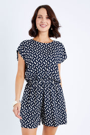 Model Andrea wearing size 10 of The Printed Tie Waist Playsuit in colour Multiprint (Black), from the front, cropped image