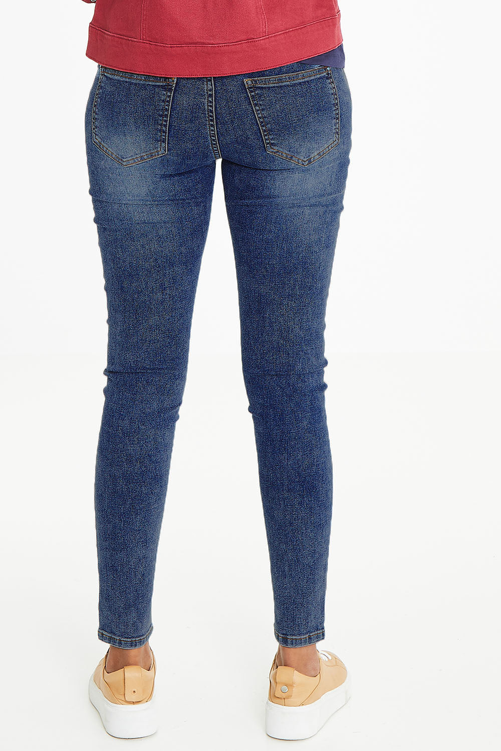 Model Schanez wearing size 10 of The Mid Rise Skinny Jean in colour Washdenim (Blue), from the back