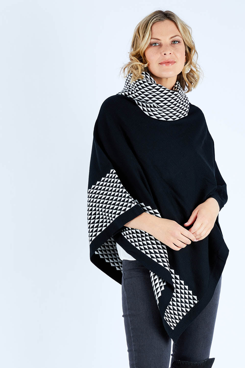 Model Chelsea wearing size S-M of The Patterned Removable Roll Neck Poncho in colour Blackprint (Black), from the front, cropped image