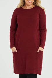 Model Katie wearing size XL of The Pocket Detail Dress in colour Burgundy (Red), from the front, cropped image