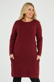 Model Katie wearing size XL of The Pocket Detail Dress in colour Burgundy (Red), from the front, cropped image