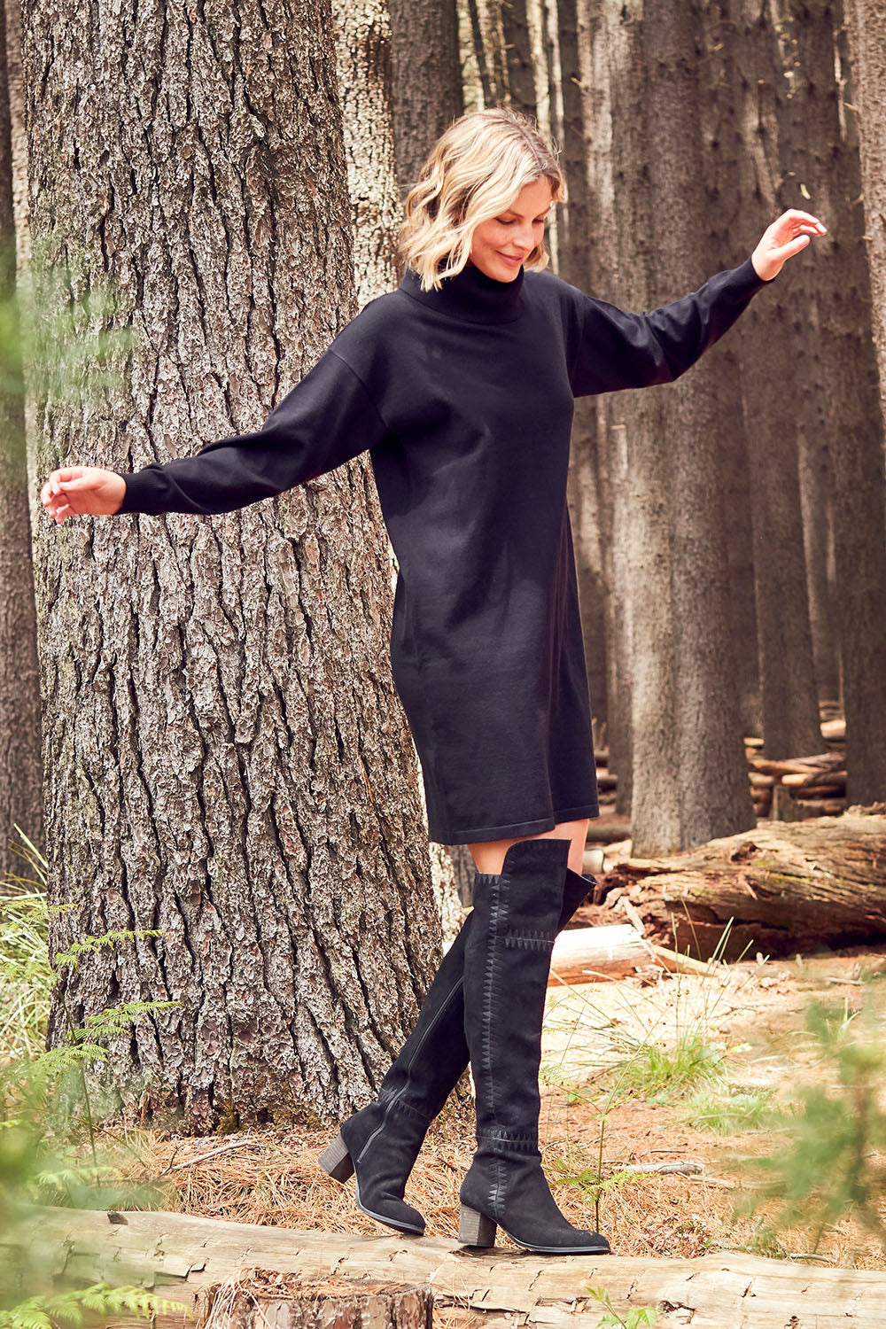 Model Chelsea wearing size S of The Roll Neck Tunic Dress in colour Black (Black), from the front, showing the whole outfit