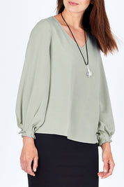 Model Rebecca wearing size 10 of The Pleated Sleeve Top in colour Sage (Green), from the front, cropped image