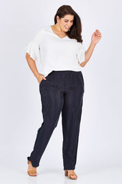 Model Mae wearing size 18 of The Curve Hem Pant in colour Ink (Blue), from the front, showing the whole outfit