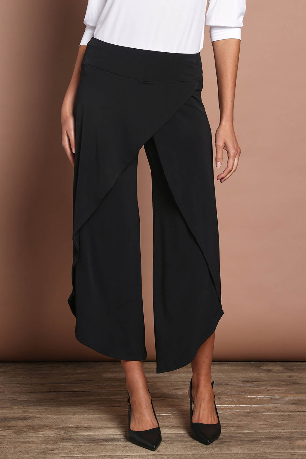 Model Madeline wearing size 10 of The Cross Over Pant in colour Black (Black), from the front, cropped image