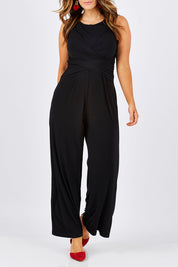 Model Laura wearing size 12 of The Cross Waist Jumpsuit in colour Black (Black), from the front, cropped image