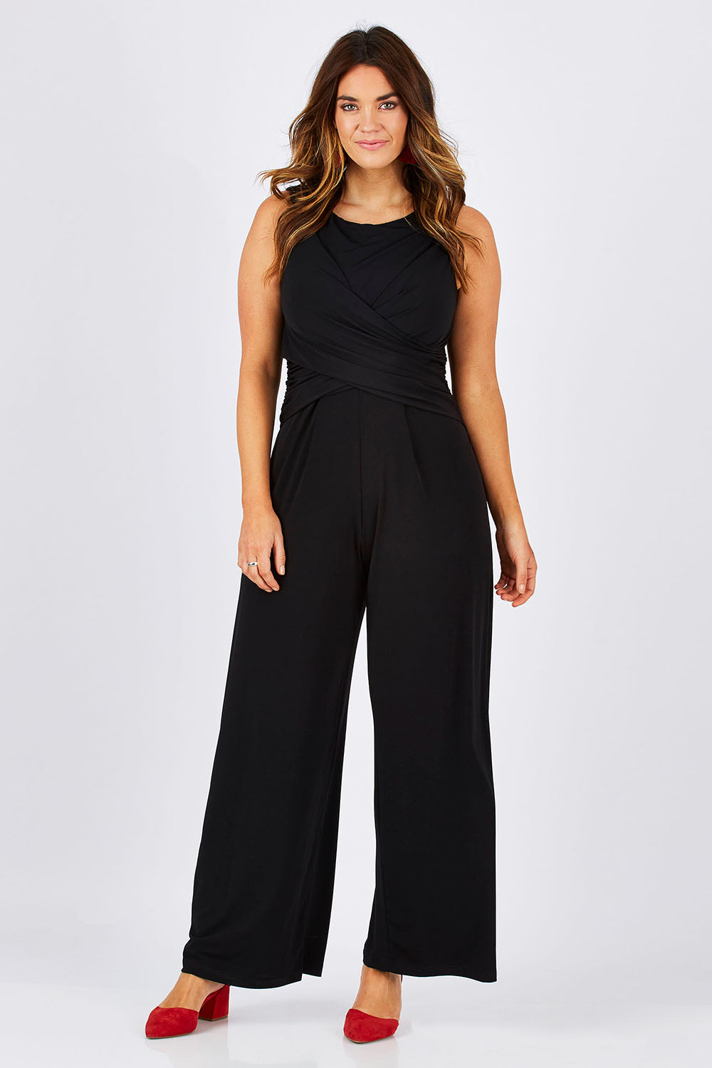 Model Laura wearing size 12 of The Cross Waist Jumpsuit in colour Black (Black), from the front, showing the whole outfit