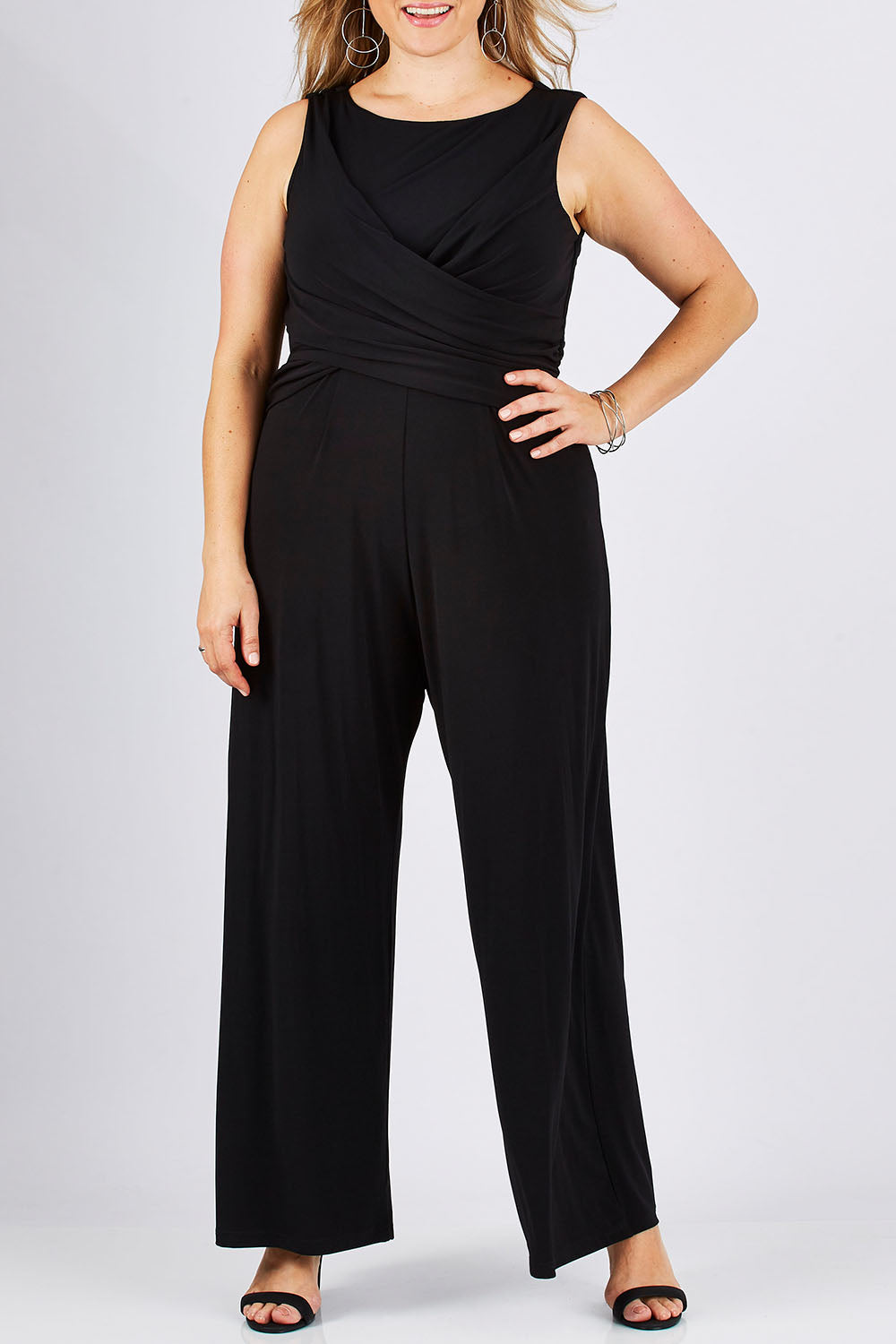 Model Ljubenka wearing size 18 of The Cross Waist Jumpsuit in colour Black (Black), from the front, cropped image