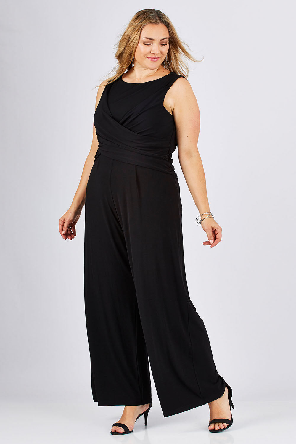 Model Ljubenka wearing size 18 of The Cross Waist Jumpsuit in colour Black (Black), from the front, showing the whole outfit