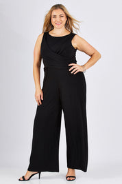 Model Ljubenka wearing size 18 of The Cross Waist Jumpsuit in colour Black (Black), from the front, showing the whole outfit