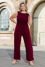 Model Fiona wearing size 16 of The Cross Waist Jumpsuit in colour Port (Purple), from the front, showing the whole outfit