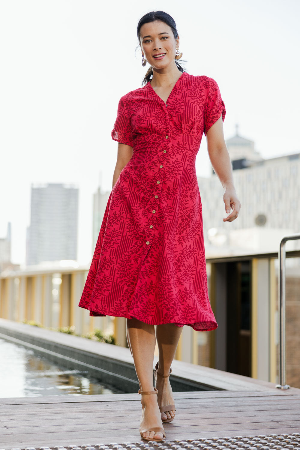 Model Miranda wearing size 10 of The Printed Cotton V Neck Dress in colour Bamboo (Red), from the front, showing the whole outfit