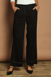 Model Madeline wearing size 10 of The Contrast Stitching Stretch Pant in colour Black (Black), from the front, cropped image
