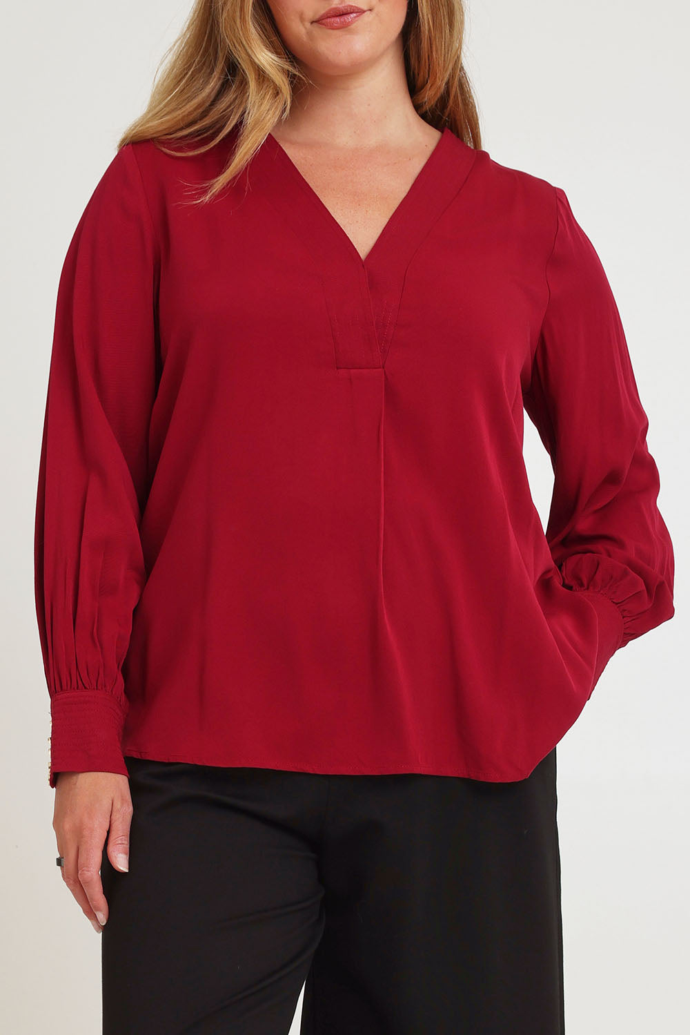 Model Chanel wearing size 16 of The Button Detail Cuff Blouse in colour Garnet (Red), from the front, cropped image