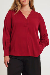 Model Chanel wearing size 16 of The Button Detail Cuff Blouse in colour Garnet (Red), from the front, cropped image
