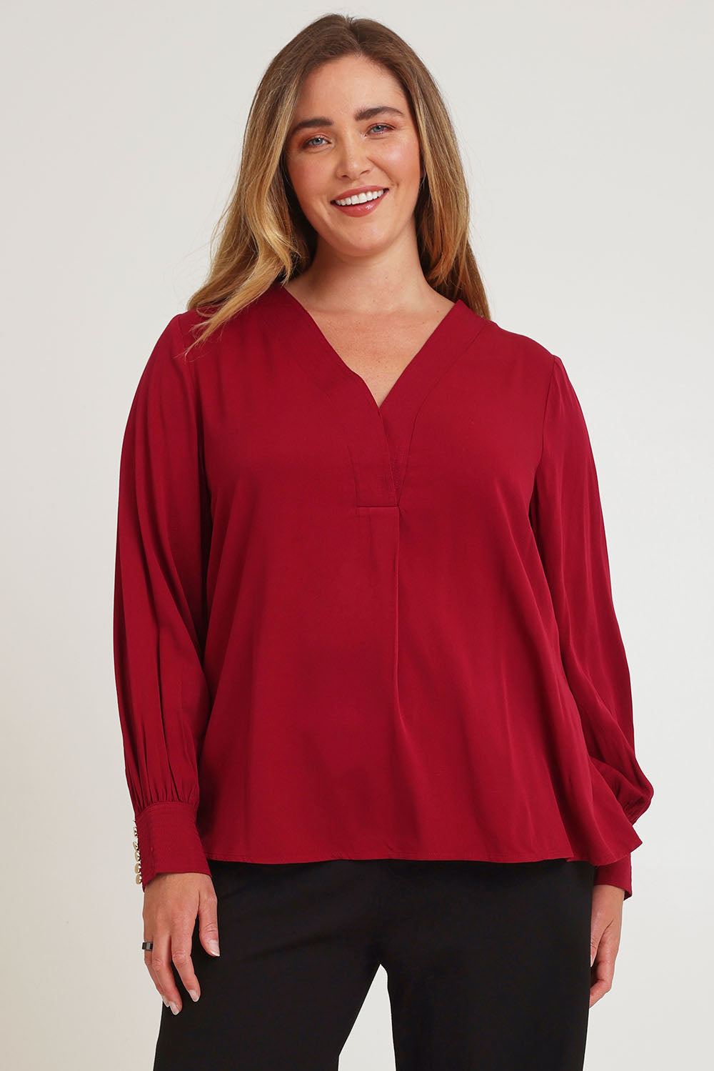 Model Chanel wearing size 16 of The Button Detail Cuff Blouse in colour Garnet (Red), from the front, cropped image