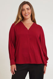 Model Chanel wearing size 16 of The Button Detail Cuff Blouse in colour Garnet (Red), from the front, cropped image