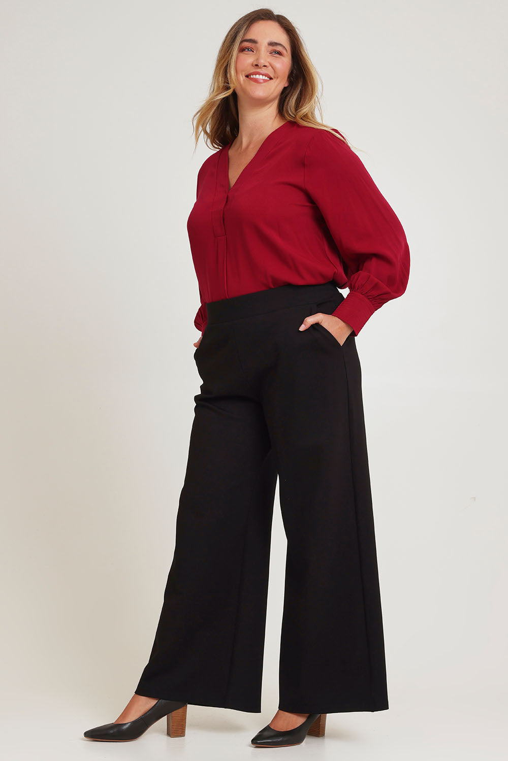 Model Chanel wearing size 16 of The Button Detail Cuff Blouse in colour Garnet (Red), from the front, showing the whole outfit