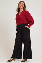 Model Chanel wearing size 16 of The Button Detail Cuff Blouse in colour Garnet (Red), from the front, showing the whole outfit