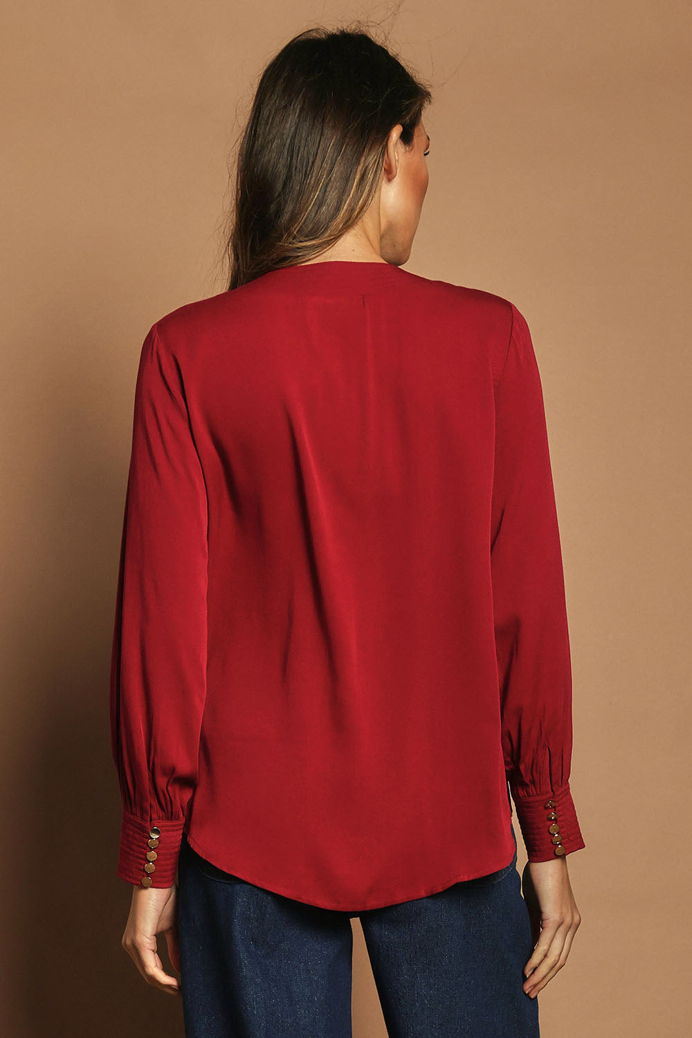 Model Madeline wearing size 10 of The Button Detail Cuff Blouse in colour Garnet (Red), from the back