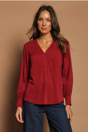 Model Madeline wearing size 10 of The Button Detail Cuff Blouse in colour Garnet (Red), from the front, showing the whole outfit