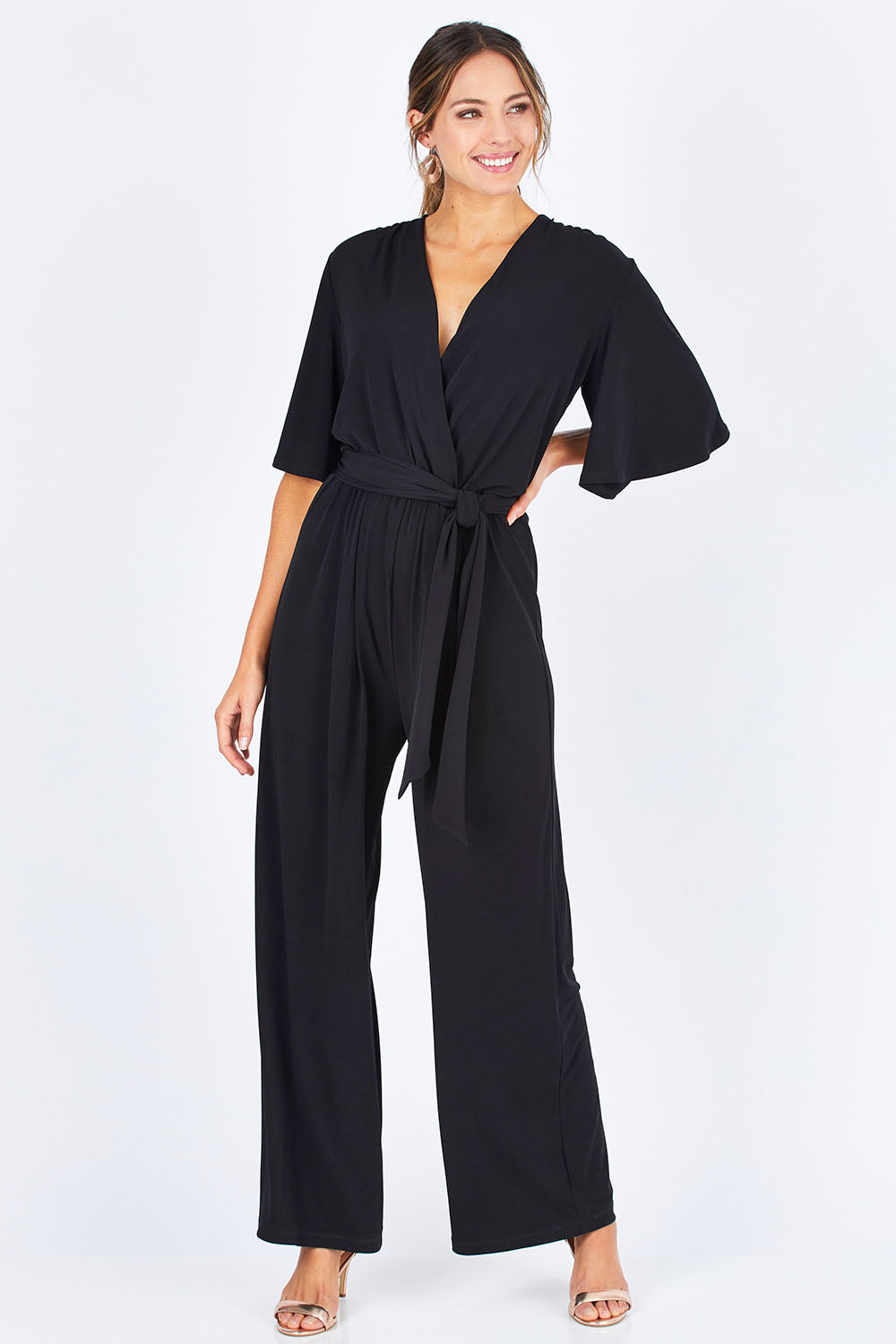 Model Madeline wearing size 10 of The Bell Sleeve Jumpsuit in colour Black (Black), from the front, showing the whole outfit