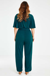 Model Laura wearing size 14 of The Bell Sleeve Jumpsuit in colour Darkteal (Green), from the back