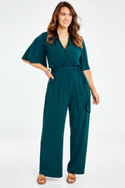 Model Laura wearing size 14 of The Bell Sleeve Jumpsuit in colour Darkteal (Green), from the front, showing the whole outfit