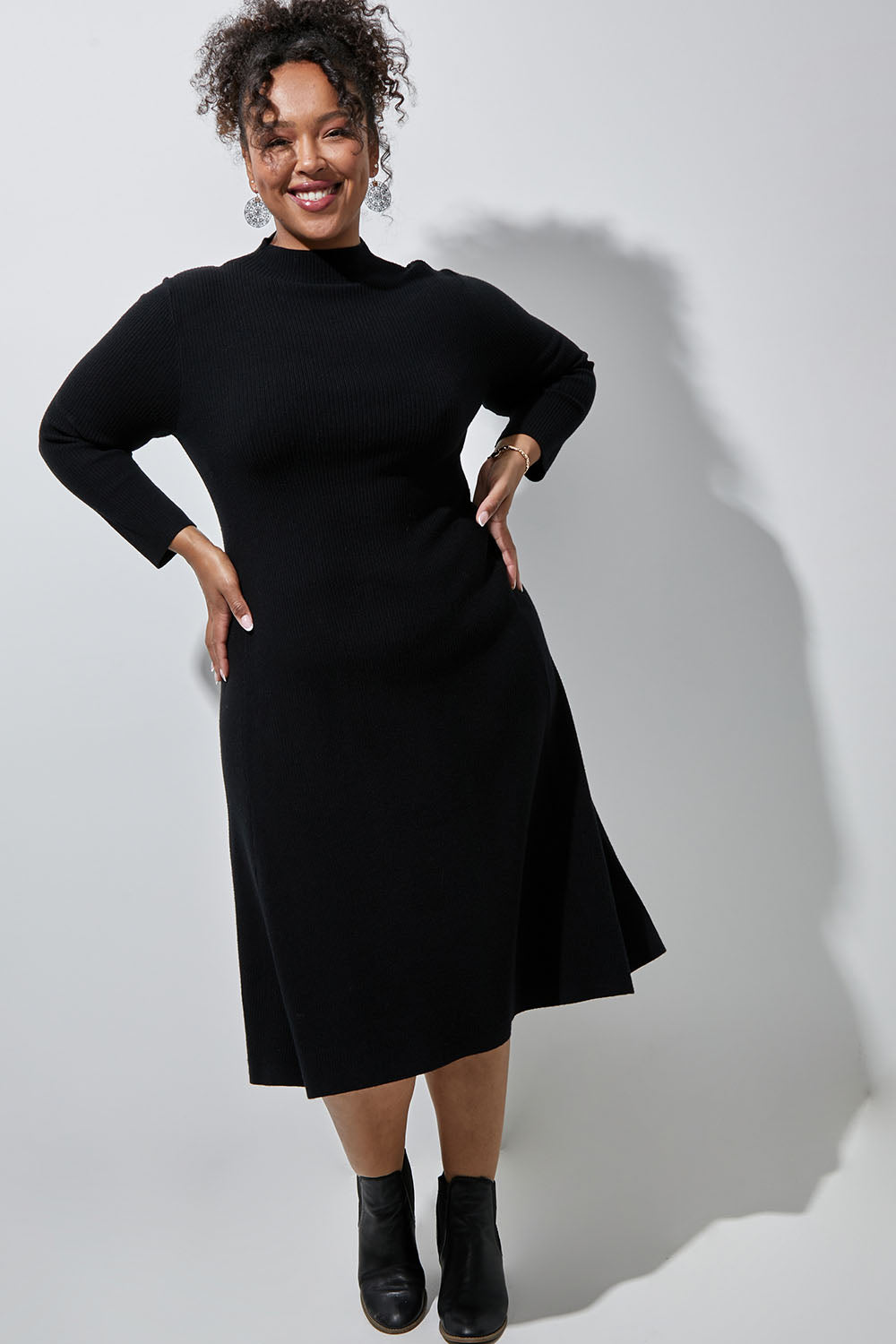 Model Alexis wearing size XL of The Fit And Flare Knitted Rib Dress in colour Black (Black), from the front, showing the whole outfit