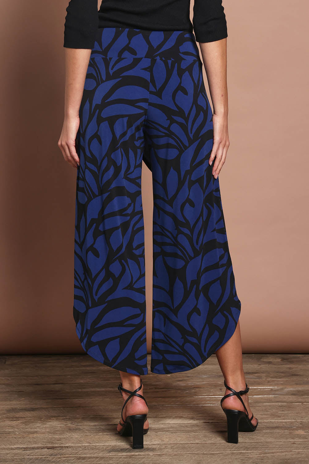 Model Madeline wearing size 10 of The Printed Cross Over Pant in colour Bluevines (Blue), from the back