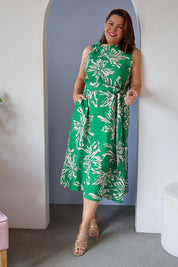 Model Stacey wearing size 16 of The Printed Adore Dress in colour Greenfleur (Green), from the front, showing the whole outfit