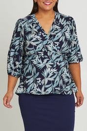 Model Ashleigh wearing size 16 of The Printed Blouson Sleeve Wrap Blouse in colour Navyleaf (Blue), from the front, cropped image