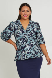 Model Ashleigh wearing size 16 of The Printed Blouson Sleeve Wrap Blouse in colour Navyleaf (Blue), from the front, cropped image