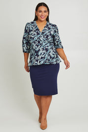 Model Ashleigh wearing size 16 of The Printed Blouson Sleeve Wrap Blouse in colour Navyleaf (Blue), from the front, showing the whole outfit