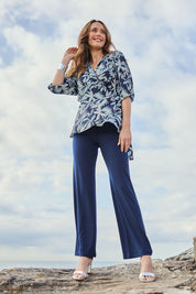 Model Clementine wearing size 10 of The Printed Blouson Sleeve Wrap Blouse in colour Navyleaf (Blue), from the front, showing the whole outfit