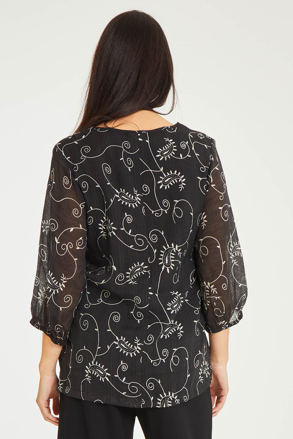 Model Stacey wearing size 10 of The Lined V Neck Blouse in colour Vines (Black), from the back