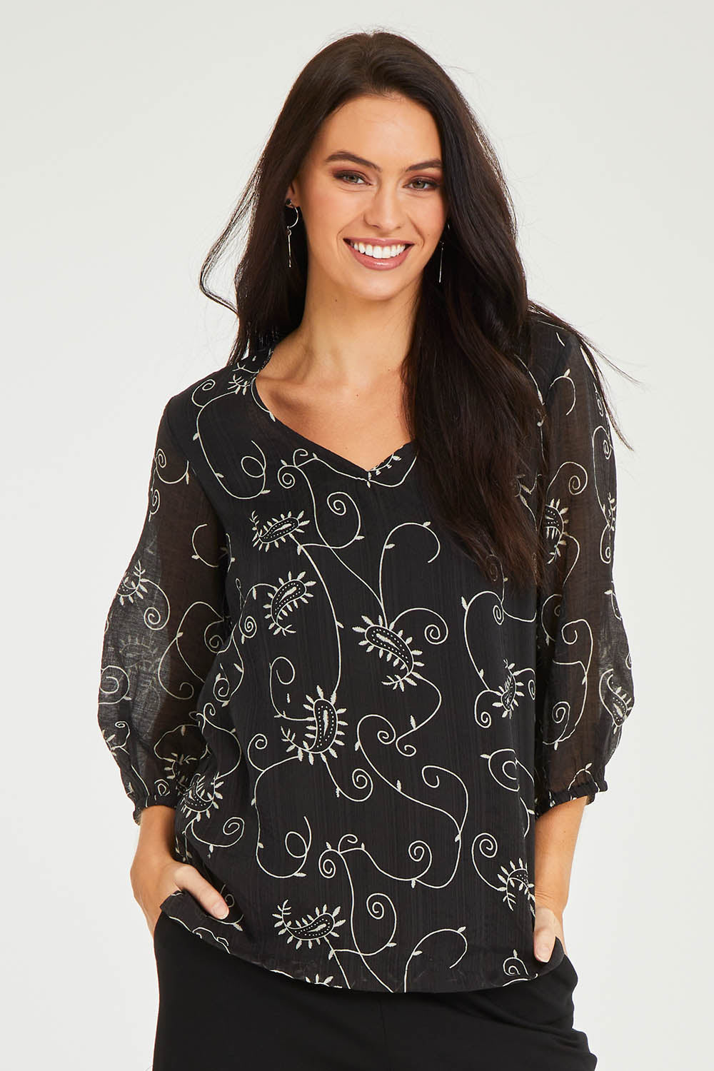 Model Stacey wearing size 10 of The Lined V Neck Blouse in colour Vines (Black), from the front, cropped image