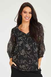 Model Stacey wearing size 10 of The Lined V Neck Blouse in colour Vines (Black), from the front, cropped image