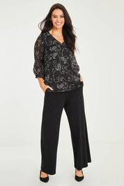 Model Stacey wearing size 10 of The Lined V Neck Blouse in colour Vines (Black), from the front, showing the whole outfit