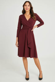 Model Madeline wearing size 10 of The Fit And Flare Ponte Dress in colour Burgundy (Red), from the front, showing the whole outfit