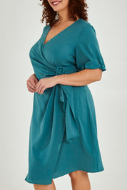 Model Maddy wearing size 16 of The Buckle Detail Faux Wrap Dress in colour Lagoon (Green), from the front, cropped image
