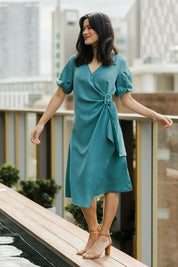 Model Miranda wearing size 10 of The Buckle Detail Faux Wrap Dress in colour Lagoon (Green), from the front, showing the whole outfit