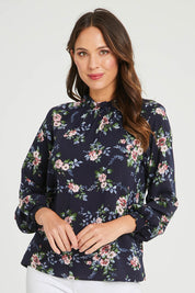 Model Madeline wearing size 10 of The Smocking Detail Printed Top in colour Flower (Blue), from the front, cropped image